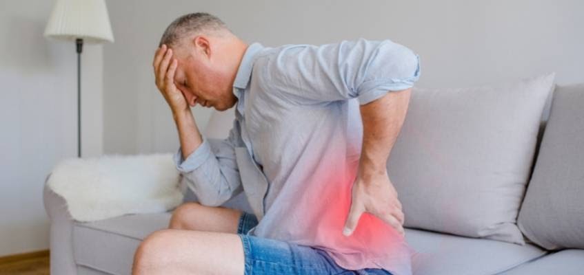 В чем же причина у мужчин? Мужчина сиди на диване и держится за поясницу