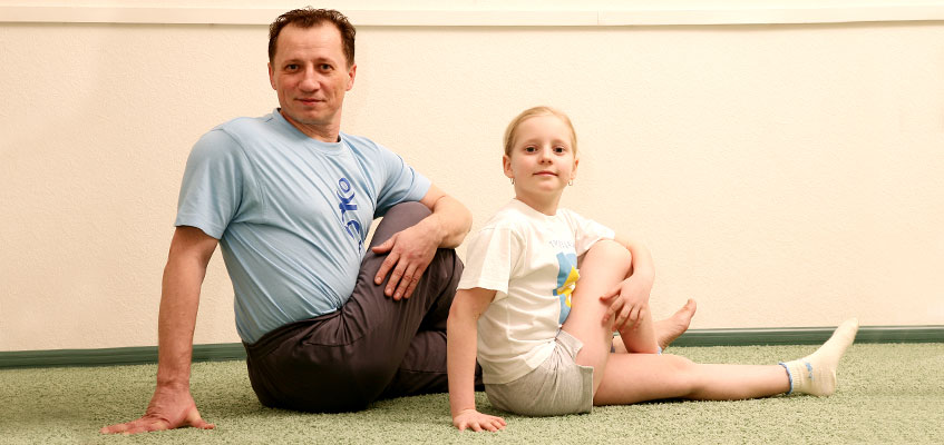 Семейные занятия имеют двойную пользу Мужчина и девочка делают йогу