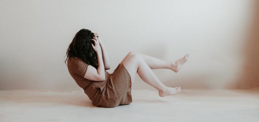 Все дело в гормонах Девушка сидит на полу взявшись за лицо